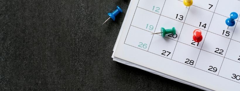 A picture of a monthly calendar on the table with pins